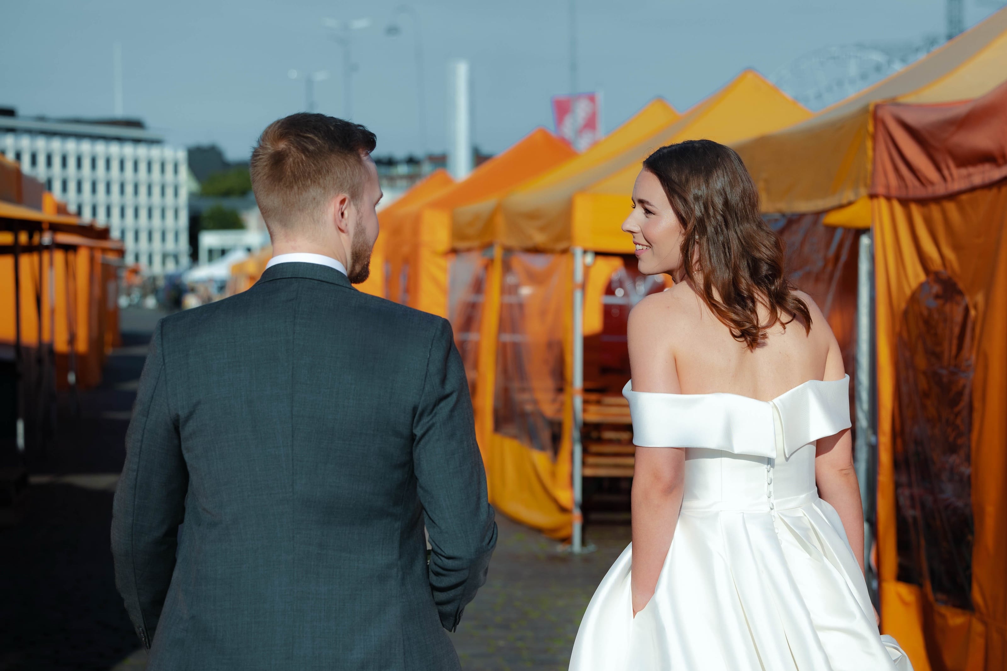 Bride and groom walking between market tents